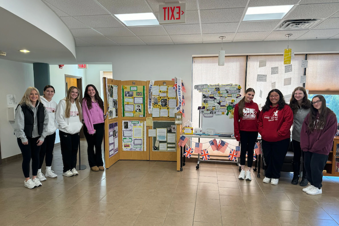 Students in Honors Course stand in front of display on Women's Suffrage Movement